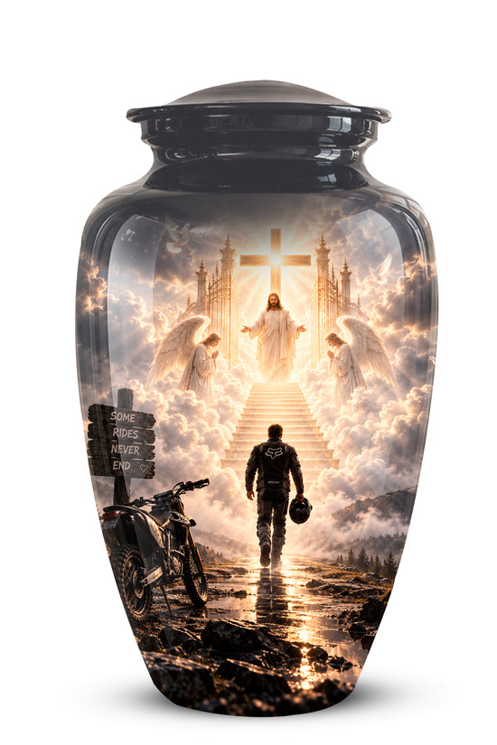 A glossy black ceramic cremation urn with a detailed religious scene printed on the front. The design shows a figure walking up steps toward a glowing cross and angels, with a motorcycle in the foreground, set against a plain white background.