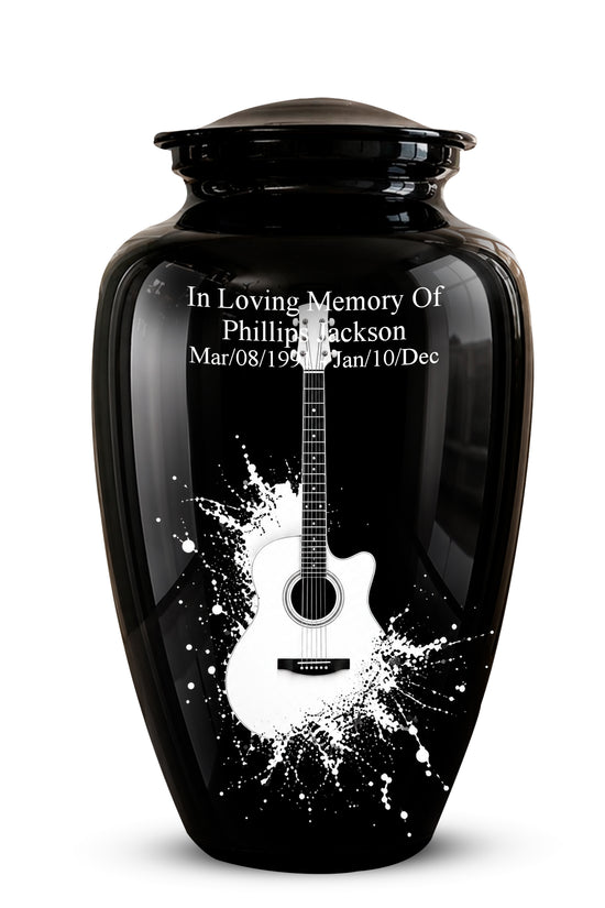 A glossy black memorial urn with a lid, featuring a white acoustic guitar graphic and white engraved text reading 'In Loving Memory Of Phillip Jackson' with dates below, shown on a light gray background.