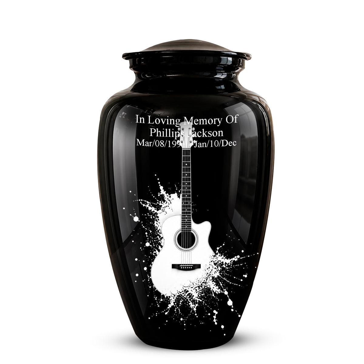 A glossy black memorial urn with a lid, featuring a white acoustic guitar graphic and white engraved text reading 'In Loving Memory Of Phillip Jackson' with dates below, shown on a light gray background.