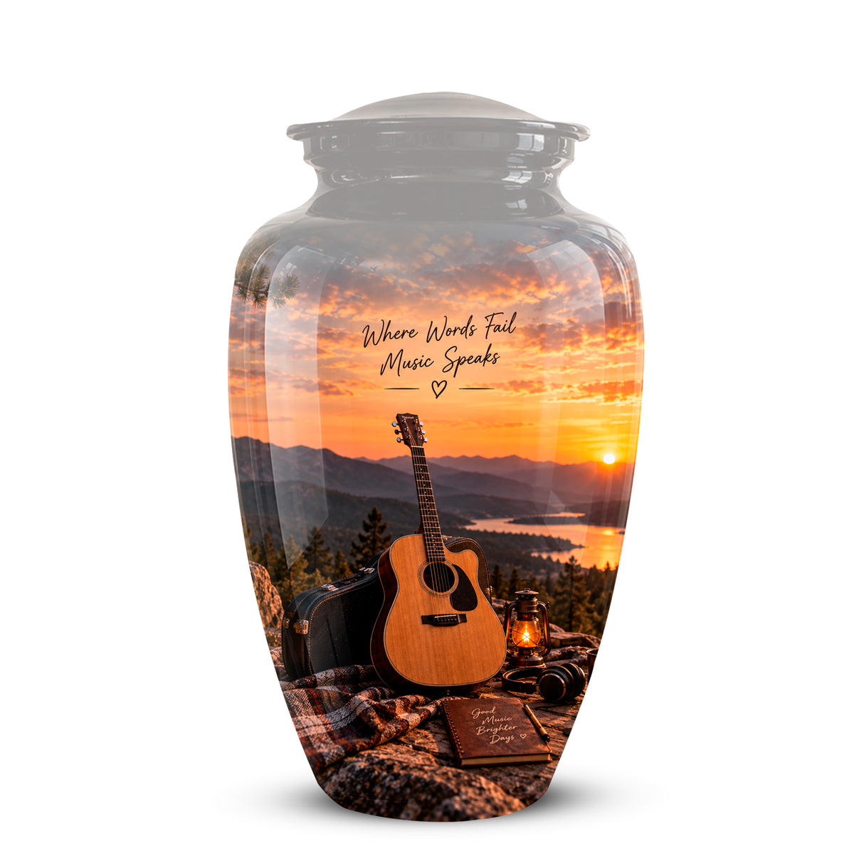 A clear glass urn with a lid, featuring a printed scenic design of an acoustic guitar, a lantern, and a book on a blanket in front of a mountain sunset over water. The text 'Where Words Fail Music Speaks' is printed on the front.