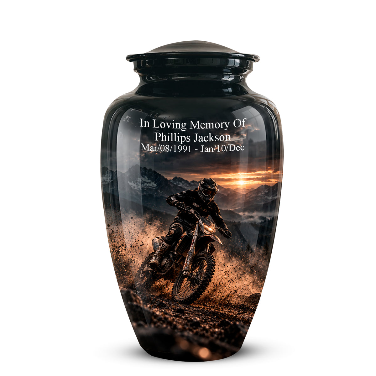 A glossy black memorial urn with a custom printed graphic of a dirt bike rider on a mountain road at sunset. White text on the upper portion reads 'In Loving Memory Of Phillips Jackson Mar,08/1991 - Jan,10/Dec'.