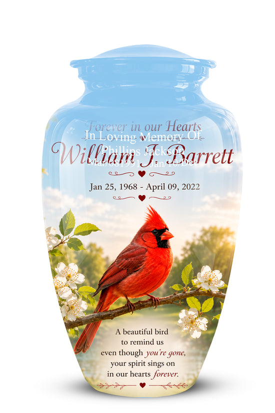 A personalized light blue glass cremation urn with a lid, featuring a printed design of a red cardinal on a flowering branch with the name 'William F. Barrett' and memorial text.