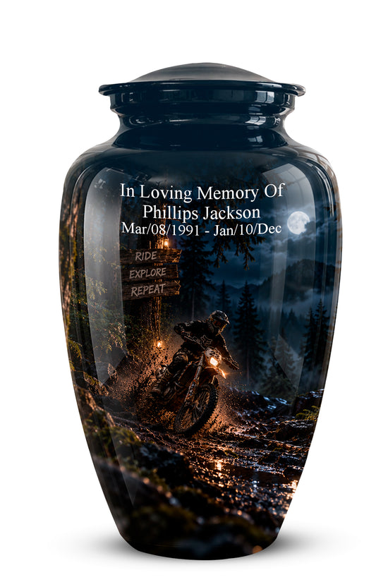 A glossy black ceramic memorial urn with a custom printed graphic of a motorcycle rider on a dark forest road at night. The urn features white personalized text reading 'In Loving Memory Of Phillips Jackson' with dates and a motorcycle sign on the front.