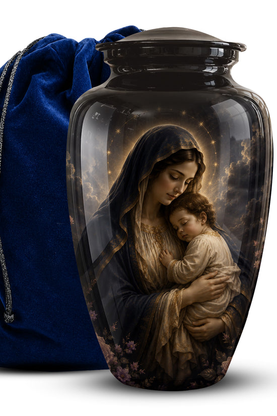 A glossy black cremation urn featuring a printed religious illustration of the Virgin Mary holding a child, shown next to a royal blue velvet drawstring bag on a white background.