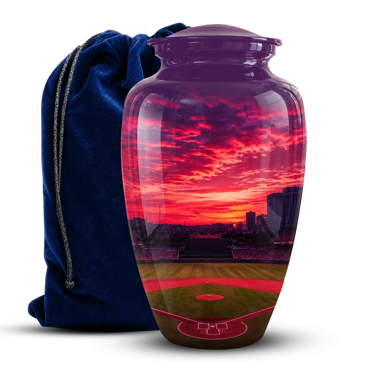 A glossy ceramic cremation urn shaped like a baseball stadium, printed with a vivid sunset scene in red, pink, orange, and green, shown next to a dark blue velvet drawstring bag on a white background.