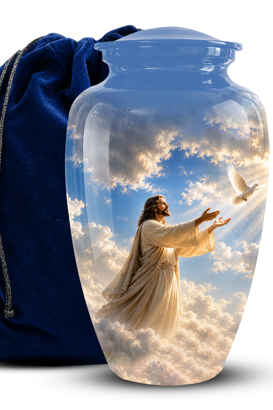 A clear glass or acrylic urn-shaped vase with a printed image of Jesus reaching toward a dove in a blue sky and clouds, shown next to a dark blue velvet drawstring bag on a white background.