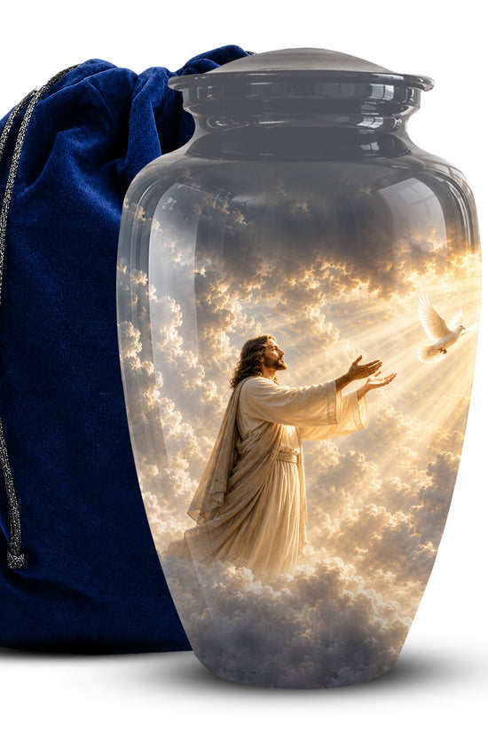 A clear glass cremation urn with a printed celestial scene of Jesus reaching toward a white dove amidst golden clouds, shown next to a dark blue velvet drawstring bag on a white background.