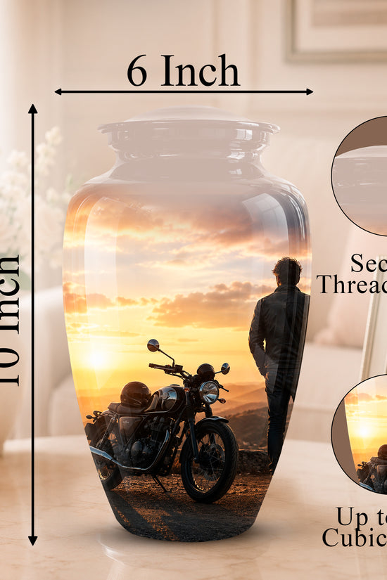 A 10-inch by 6-inch ceramic memorial vase with a printed motorcycle and sunset scene, shown on a tabletop with dimension callouts and inset detail circles for the threaded lid and printed design.