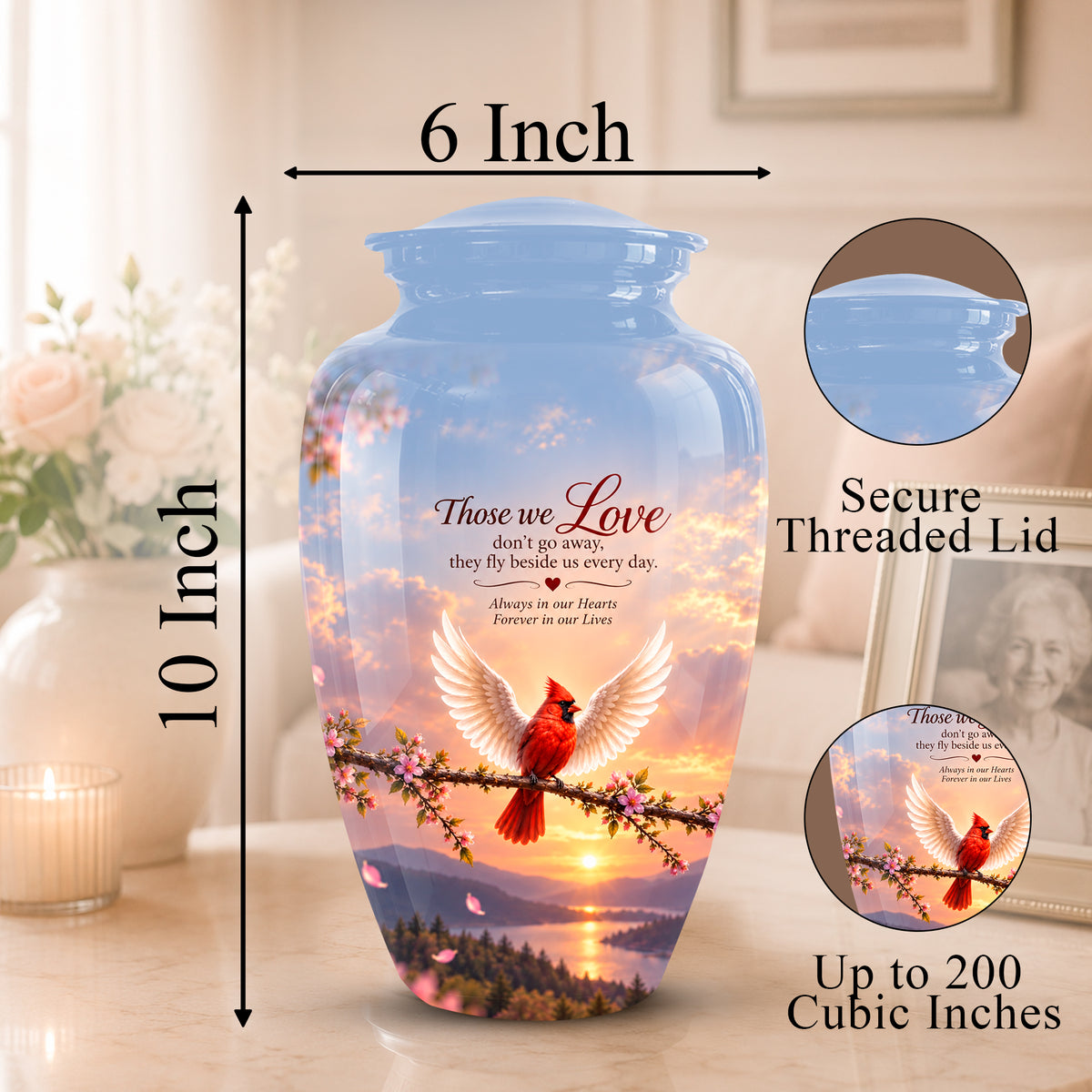 A printed ceramic cremation urn shown on a tabletop with dimension arrows indicating 10-inch height and 6-inch width. The urn has a blue threaded lid and a scenic print of a red cardinal on a branch at sunset, with memorial text reading 'Those we Love.