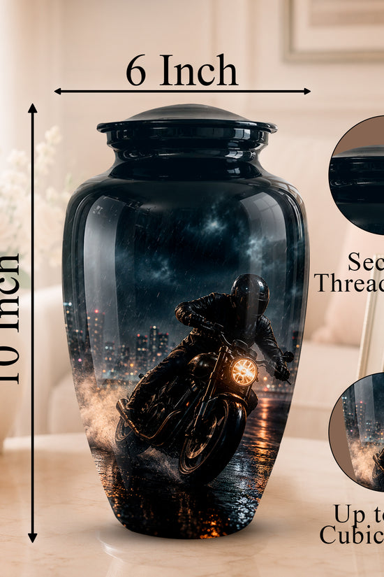 A glossy black ceramic cremation urn with a printed motorcycle rider over a city skyline design, shown on a tabletop with dimension labels reading 6 Inch and 10 Inch, plus circular inset close-ups of the lid and printed detail.
