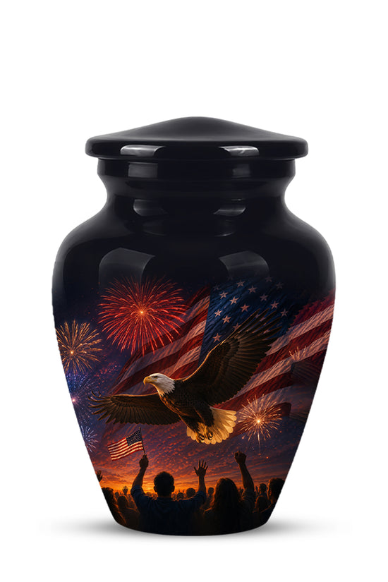 A glossy black cremation urn with a lid, featuring a detailed patriotic graphic of a bald eagle flying over fireworks, an American flag, and silhouettes of a crowd at the bottom.