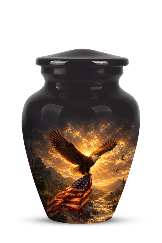 A glossy black cremation urn with a lid, featuring a printed graphic of an eagle flying over a mountain landscape with a waving American flag and a bright sunset sky.