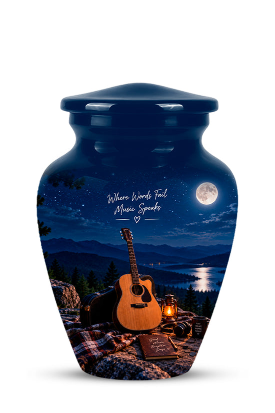 A dark blue urn-shaped vase with a lid, featuring a printed scenic graphic of a night campsite with an acoustic guitar, lantern, mountains, lake, moon, and the words 'Where Words Fail Music Speaks'.