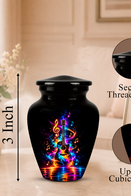 Black cremation urn with a colorful neon guitar and musical note design, shown on a tabletop with a blurred living room background. The image includes a 3-inch height marker, a close-up inset of the secure threaded lid, and a close-up inset of the printed design.