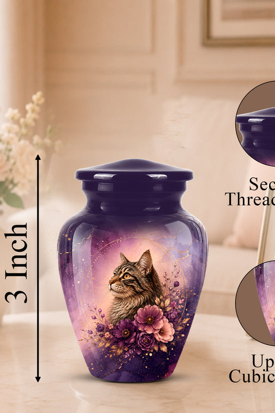 A purple and lavender cremation urn with a printed tabby cat and floral design, shown on a tabletop in a softly lit room. The image includes a 3-inch height marker, a close-up inset of the secure threaded lid, and a circular detail inset showing the printed artwork up to 3 cubic inches.