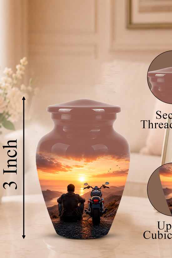 A glossy ceramic cremation urn with a threaded lid, featuring a printed sunset scene of a man and motorcycle. The image includes a 3-inch height marker, a close-up of the secure lid, and a circular inset showing up to 3 cubic inches of space for a photo.
