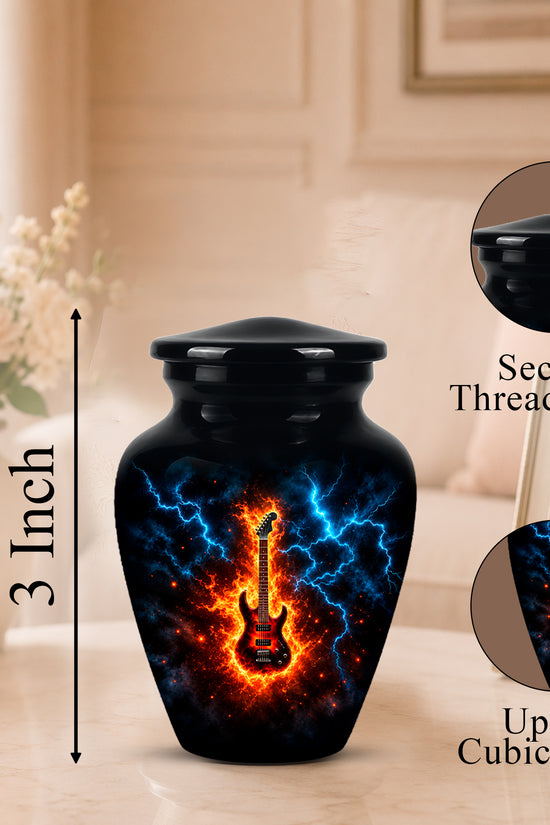 Black cremation urn with a glowing electric guitar design and blue lightning effects, shown on a tabletop with a blurred living room background. Callouts indicate a secure threaded lid, 3-inch height, and up to 3 cubic inches capacity.