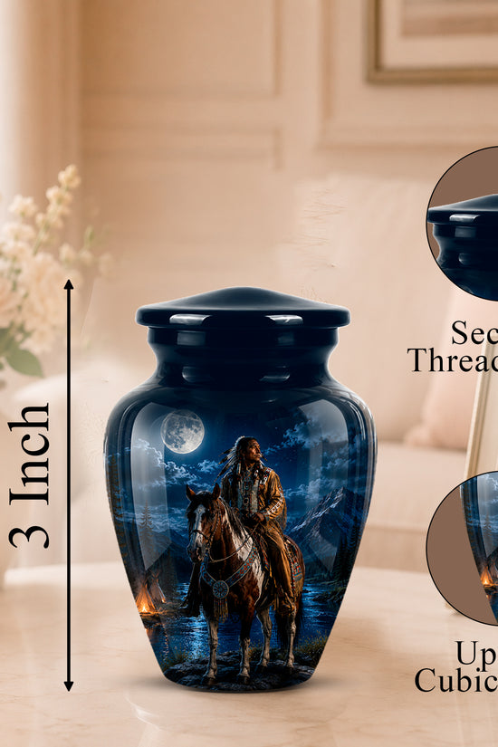 A glossy dark blue urn-shaped memorial vase with a printed night-sky scene showing a rider on horseback and a full moon. The vase sits on a tabletop in a softly lit indoor setting, with a 3-inch height marker, a close-up inset of the secure threaded lid, and a close-up inset of the printed design.
