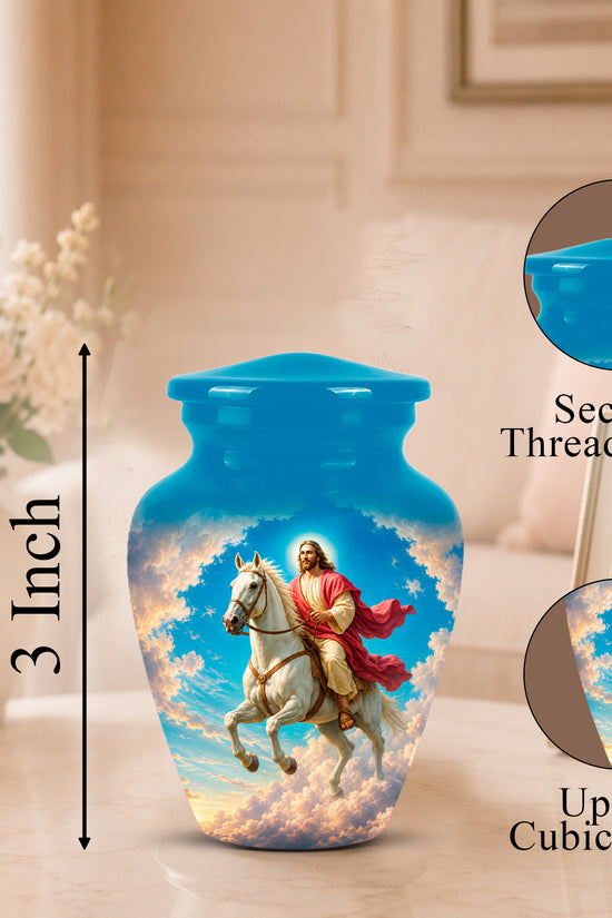 Blue ceramic cremation urn with a printed religious scene of Jesus riding a white horse through clouds, shown on a tabletop in a softly lit room. Black measurement text reads 3 Inch, with circular inset close-ups of the secure threaded lid and the printed design, plus text noting up to 3 cubic inches.
