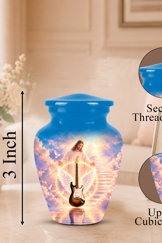 A blue urn-shaped memorial vase with a printed image of Jesus on a guitar in a glowing sky, shown on a tabletop with a framed photo and flowers in the background. Callout graphics indicate a 3-inch height and mention a secure threaded lid and up to 3 cubic inches capacity.