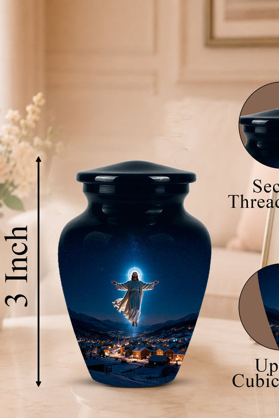A glossy black urn-shaped cremation vase with a printed image of Jesus over a glowing village at night, shown on a tabletop in a softly lit room. A vertical arrow labels the height as 3 Inch, and two circular inset callouts on the right show the secure threaded lid and up to 3 cubic inch capacity.