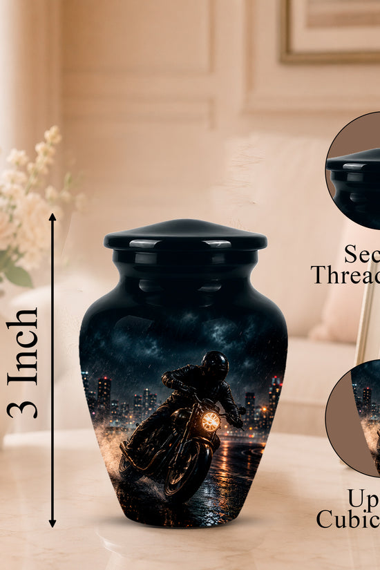 A black ceramic cremation urn with a printed motorcycle and city skyline design, shown on a tabletop in a softly lit room. The image includes a 3-inch height marker, a close-up inset of the secure threaded lid, and a close-up inset of the printed surface with text reading 'Up to 3 Cubic Inches'.