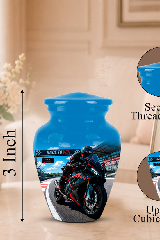 Blue ceramic cremation urn with a printed motorcycle racing graphic, shown on a tabletop with a flower vase and framed photo in the background. The image includes a 3-inch height marker, a close-up inset of the secure threaded lid, and a circular inset showing up to 3 cubic inches of space.