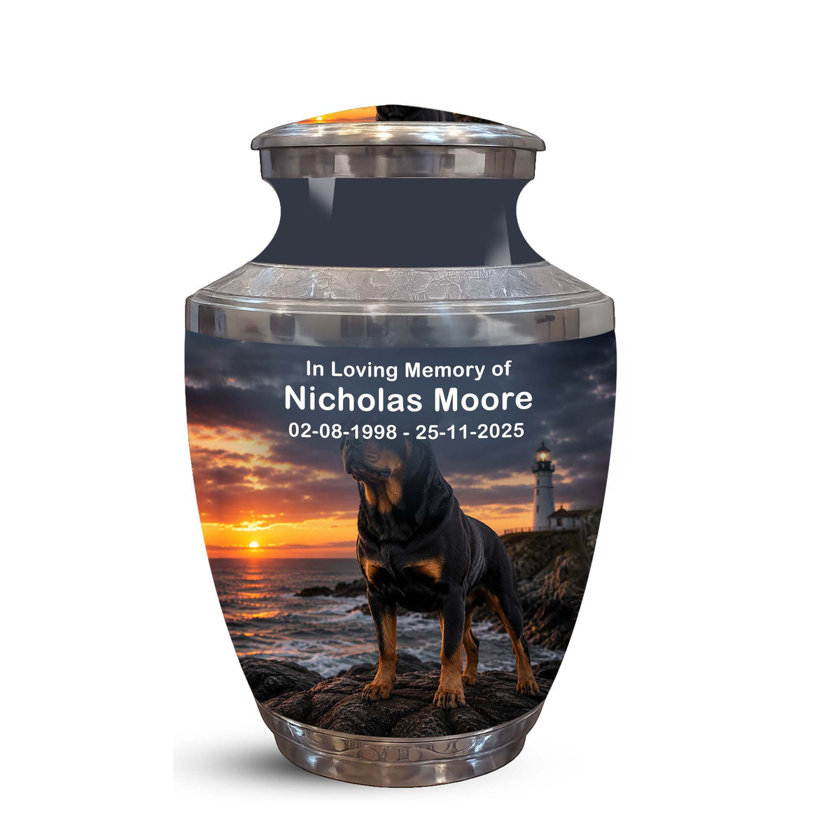 A memorial urn with a custom printed photo of a black and tan dog standing by the ocean at sunset, with the text 'In Loving Memory of Nicholas Moore 02-08-1998 - 25-11-2025' on the front. The urn has a dark gray body, silver metallic top and base, and is shown on a plain white background.