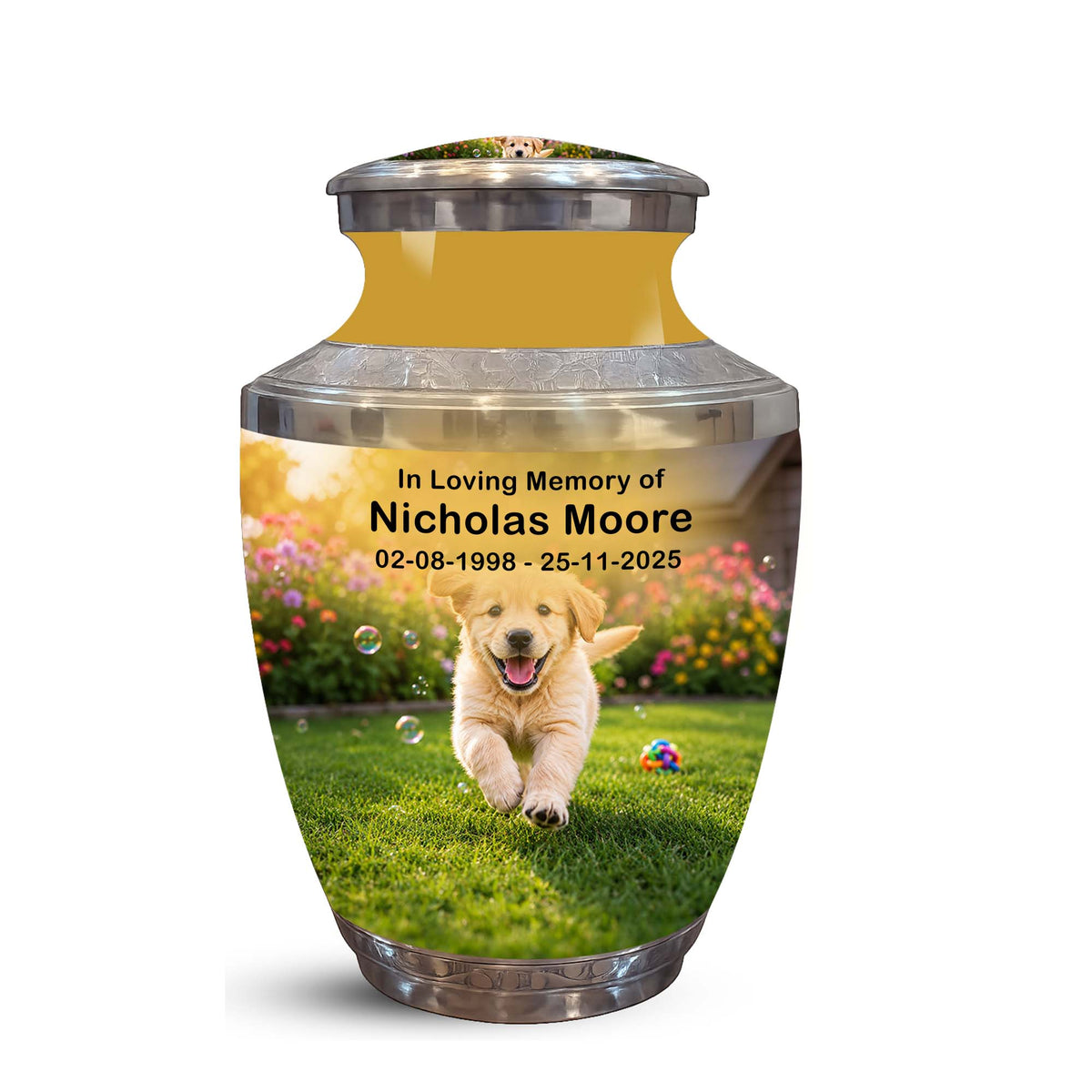 A memorial urn with a printed photo of a golden retriever puppy on a grassy lawn, with the text 'In Loving Memory of Nicholas Moore 02-08-1998 - 25-11-2025'. The urn has a metallic gold interior, a silver metallic lid and base, and is shown on a plain white background.