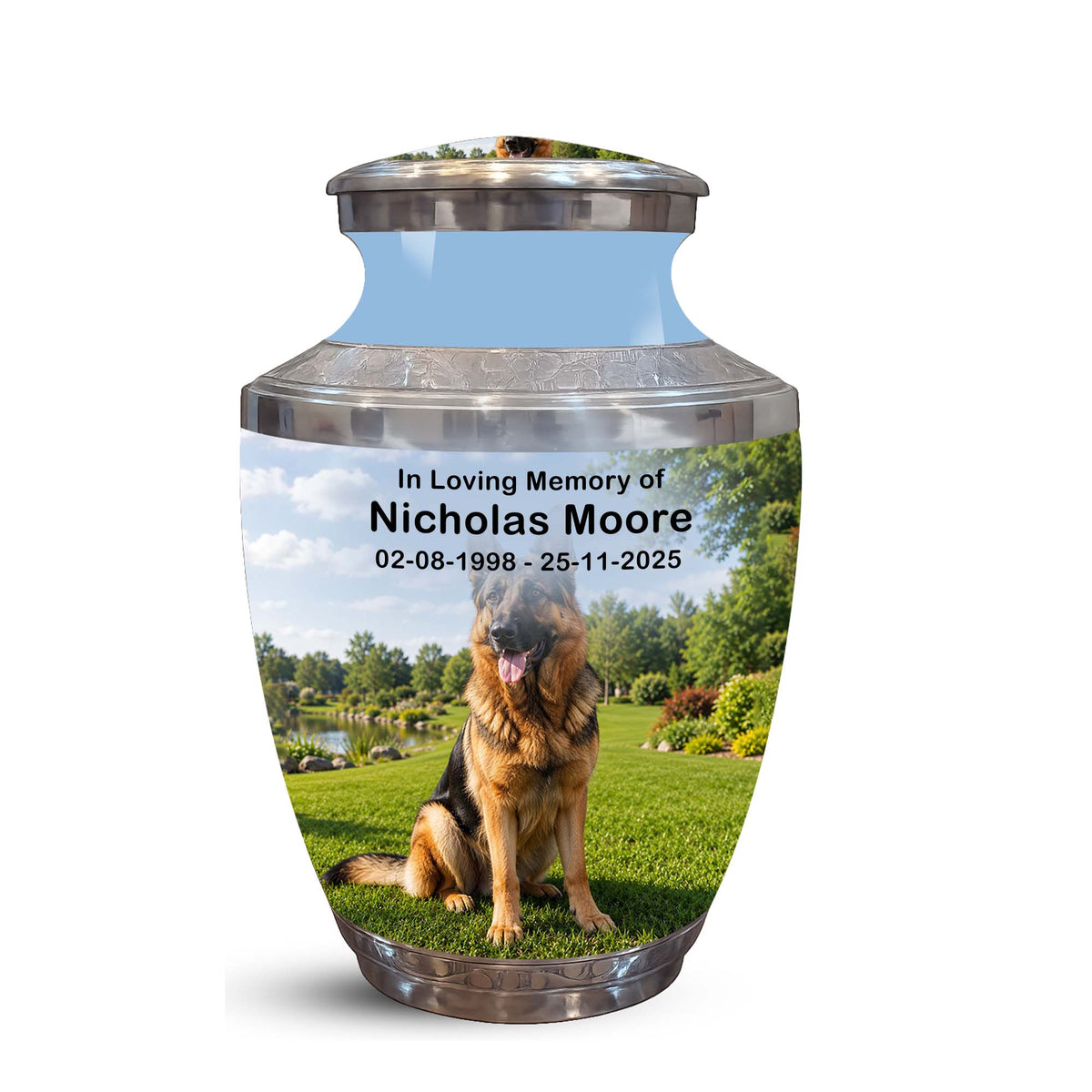 A memorial pet urn with a printed photo of a German Shepherd on a green lawn, with the text 'In Loving Memory of Nicholas Moore 02-08-1998 - 25-11-2025' on a white background.
