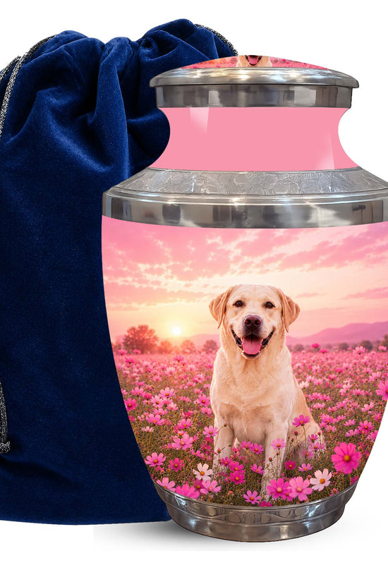 A memorial urn with a pink sky and dog in a flower field printed design, shown next to a dark blue velvet drawstring bag on a white background.