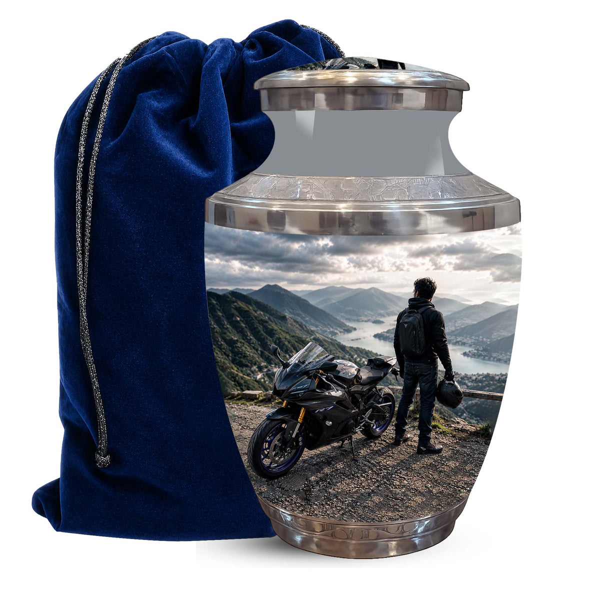 A glossy metallic cremation urn with a custom landscape photo print of a motorcyclist on a mountain road, shown next to a dark blue velvet drawstring bag on a white background.