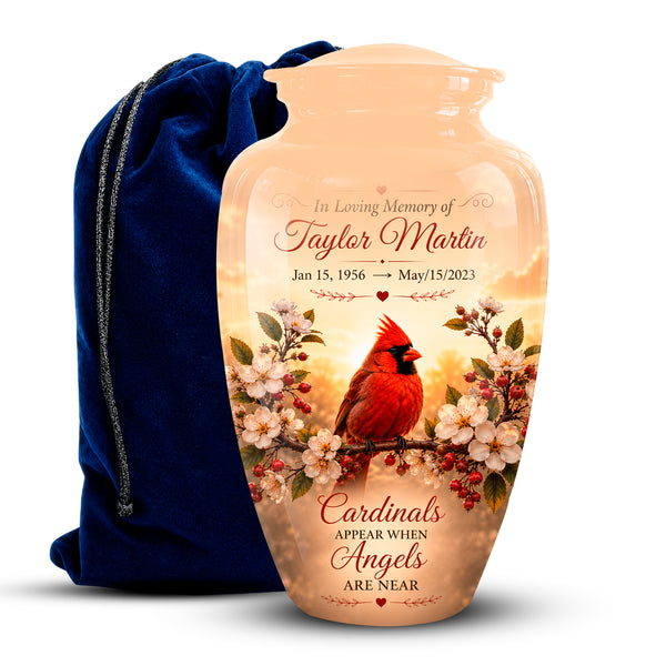 Personalized ceramic memorial urn vase with a printed cardinal and cherry blossom design, shown with a dark blue velvet drawstring bag on a white background.